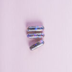 three-transparent-sequin-capsules-wooden-texture-pink-backdrop